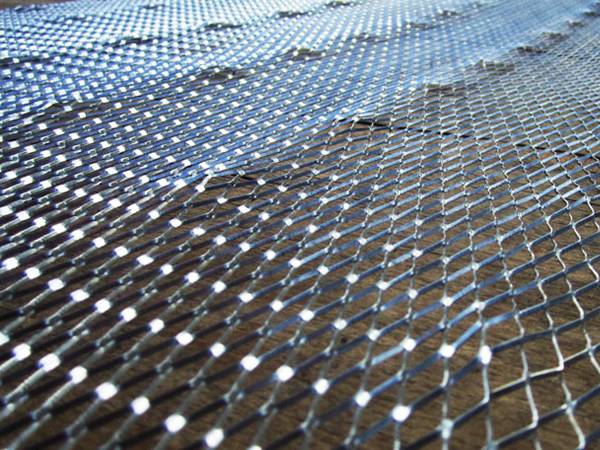 The picture of diamond metal lath with dimpled shapes in a wooden surface.